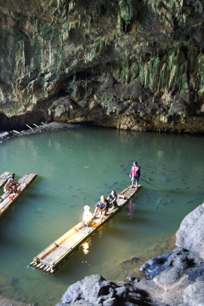 Harry and Caroline on a bamboo raft surrounded by fish in Tham Lod Cave